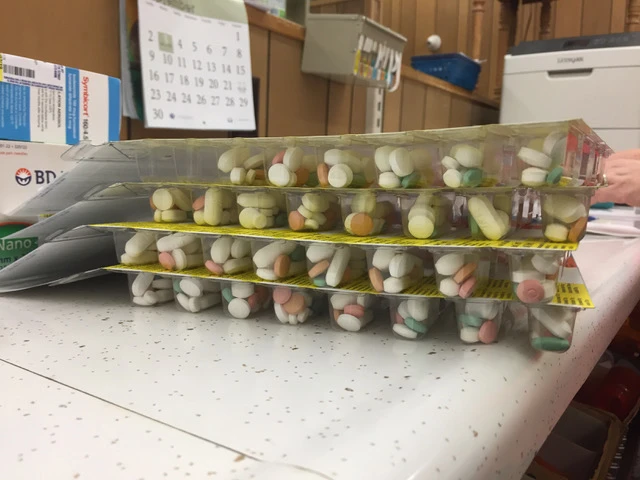 Filled Dispill cards stacked on the pharmacy counter, with pills organized into individual dose compartments