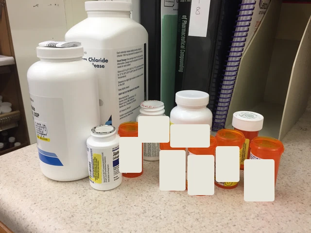 Multiple medication bottles on the pharmacy counter, with prescription labels obscured